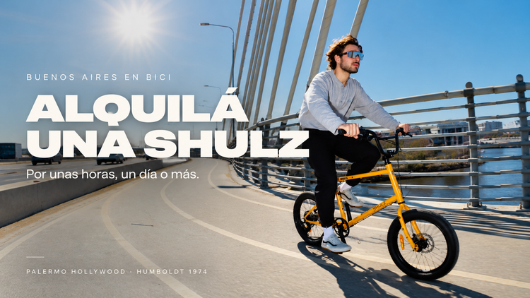 Joven andando en una bicicleta SHULZ amarilla por un puente en Buenos Aires. Texto: Alquilá una SHULZ. Por unas horas, un día o más. Palermo Hollywood, Humboldt 1974.